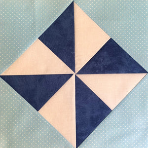 Windmill Quilt block made with triangles in Light blue, dark blue, and white.