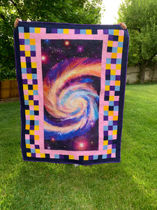 Galaxy Baby Quilt using a galaxy panel, pink, purple, blue, and yellow