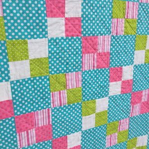 Close up of Alana Quilt Pattern - Easy quilt made in squares with pink, teal, white, and green
